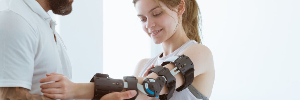 Tattooed physiotherapist who puts an orthosis on the hand of a young patient after an accident