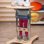 Dziecko w stójce rehabilitacyjnej w sali terapeutycznej.
