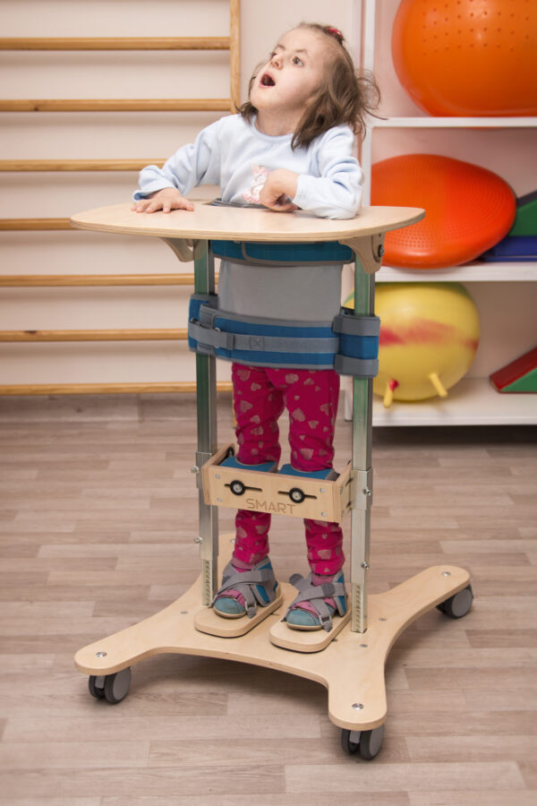 Dziecko w stójce rehabilitacyjnej w sali terapeutycznej.