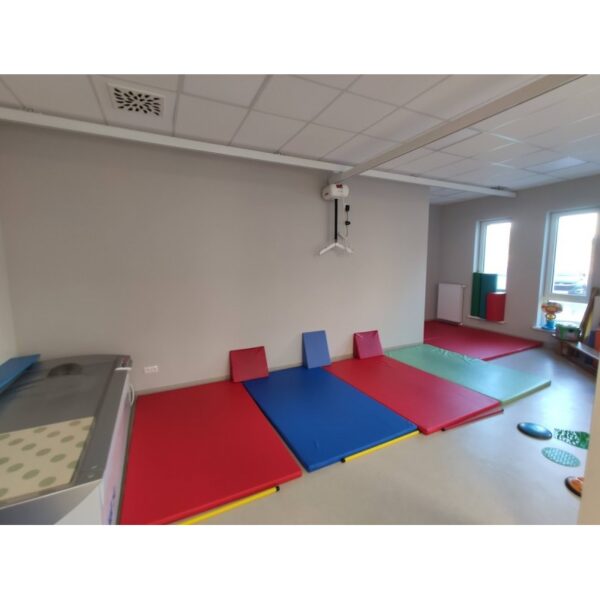 Przestrzeń do ćwiczeń z kolorowymi matami i urządzeniami rehabilitacyjnymi.