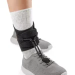 Stabilizator kostki na szarej stopie w sportowym obuwiu.