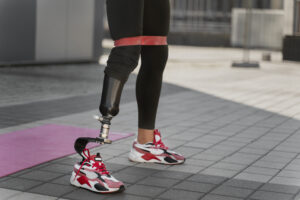 Osoba w wygodnych butach sportowych i protezą nogi na macie.