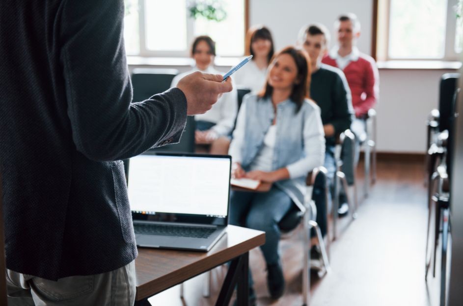 Szkolenie dla pracowników dotyczące ergonomii pracy i radzenia sobie ze stresem, prowadzone w grupie w sali szkoleniowej.